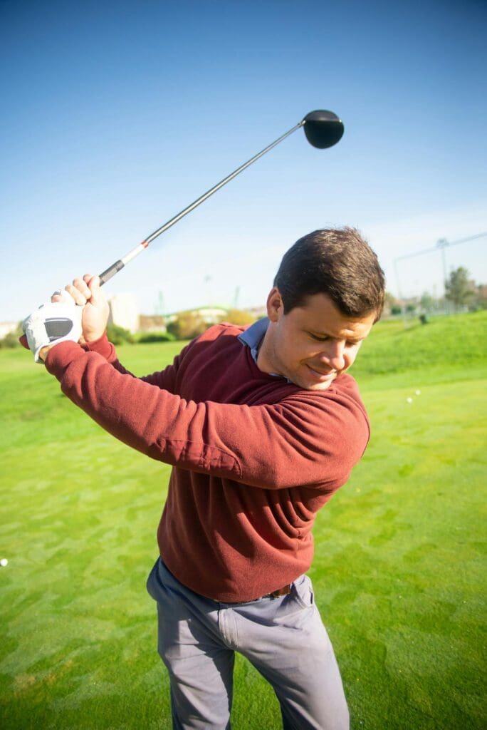 Man executing a perfect golf swing on a sunny day at a beautiful Portugal course.